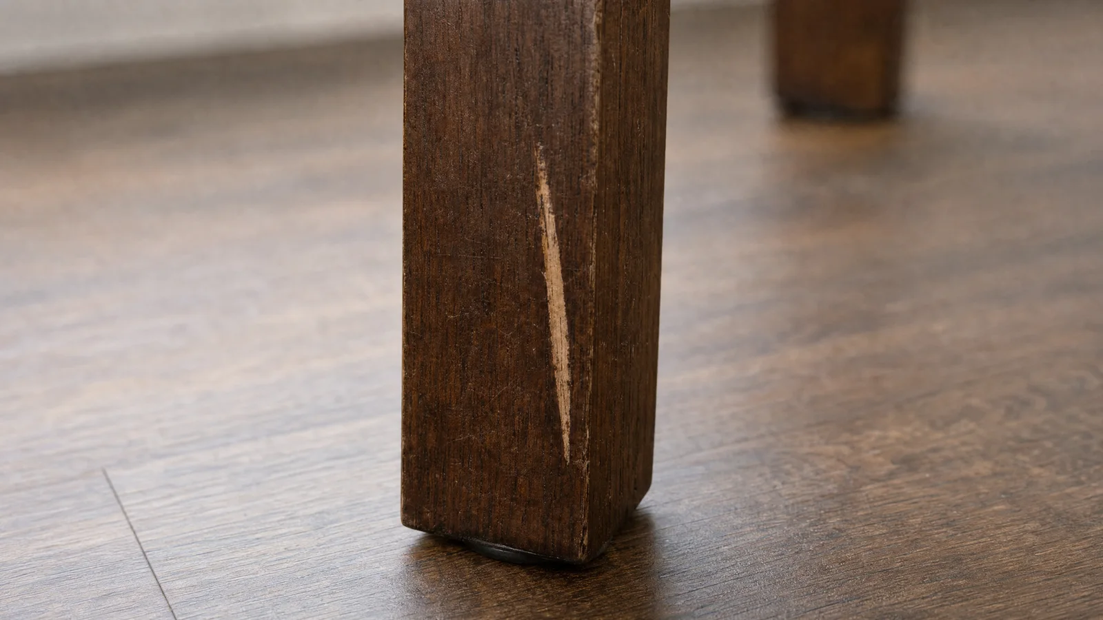 A short pale scratch on the front leg of the chair